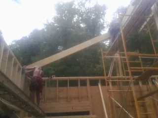 Carpenter raising a rafter beam on a new second story frame in Pebble Beach