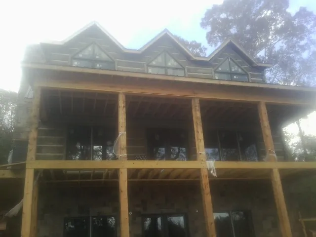 Dormers and porch framing on a large log home under construction — Roof Coating work by our crew in Pebble Beach