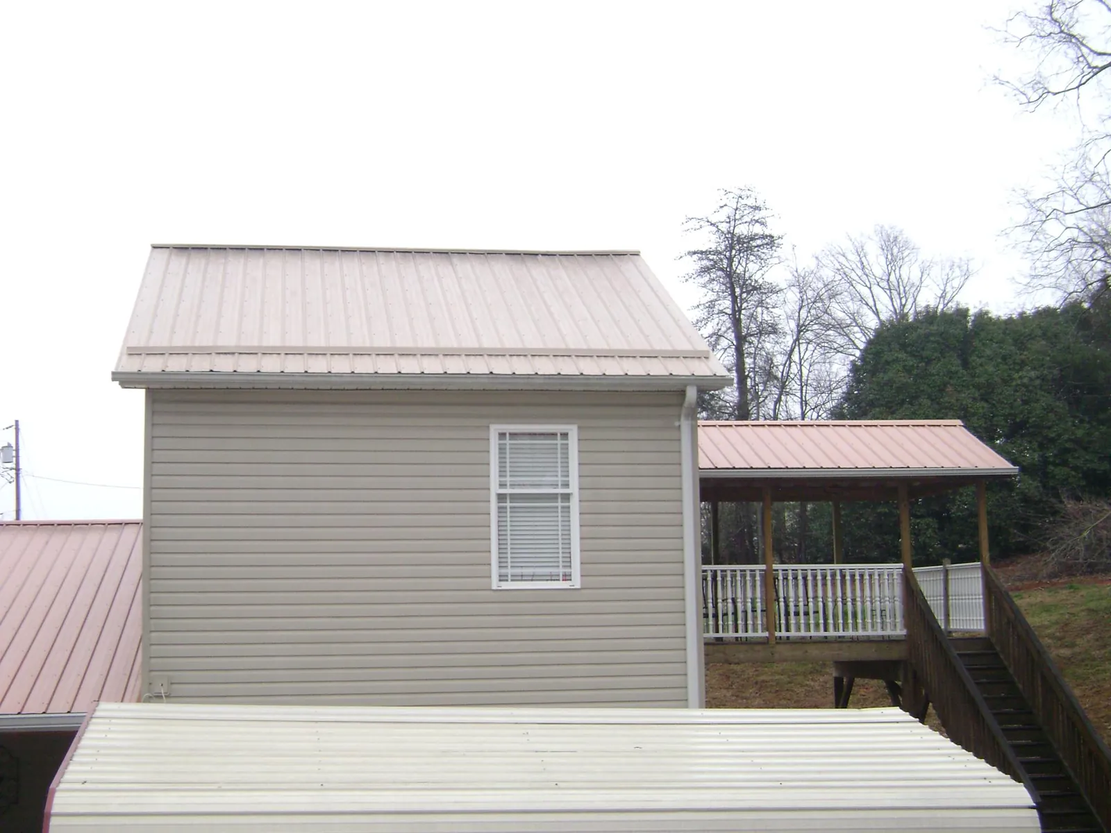 Tan metal roofs on a two story addition and attached porch, from a Roof Replacement job in Pebble Beach